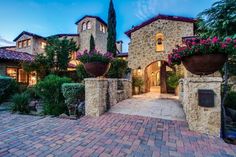 the entrance to a large home with potted plants