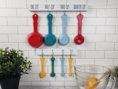 a kitchen counter with measuring cups and spoons hanging on the wall next to a potted plant