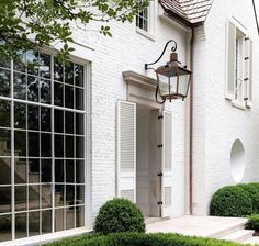 a white house with two large windows and a lamp on the side of the building