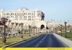 the large building has many windows on it's sides and is next to a street lined with palm trees