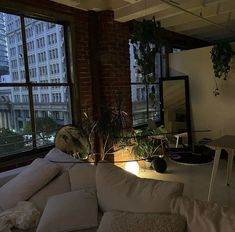 a living room filled with lots of furniture next to a large window covered in plants