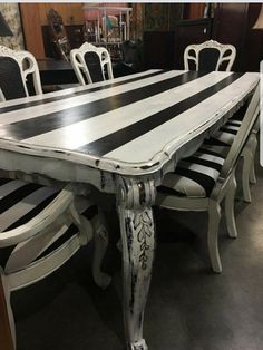 a dining room table with black and white stripes painted on the top, along with matching chairs