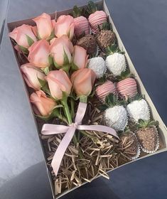 a box filled with pink roses and chocolate covered strawberries on top of a table