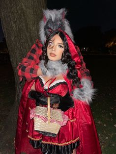 a doll dressed in a costume standing next to a tree