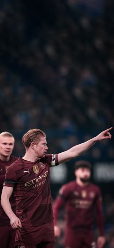 a soccer player is pointing at something while the other team looks on from behind him