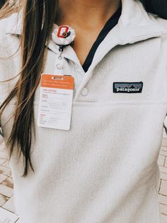 a woman wearing a white sweater with a badge on it