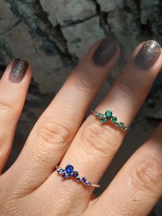 a woman's hand with two rings on it and one ring has blue stones