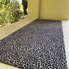 a black and white leopard print rug on the ground next to a building with trees in the background