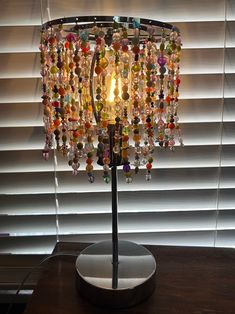 a lamp that is on top of a table next to a window covered with blinds