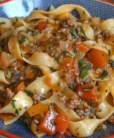 a blue plate topped with pasta covered in meat and vegtables on top of it