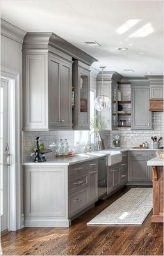 a large kitchen with wooden floors and gray cabinets