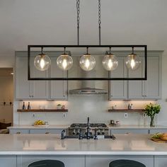 a kitchen island with stools and lights hanging over it