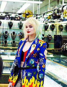 a woman with blonde hair wearing a blue jacket and red top standing in front of a store display