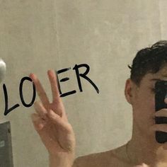 a man taking a selfie in front of a mirror with the word loer written on it