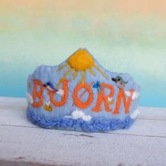 a blue felt crown with the word boorn written in orange and white on it