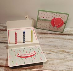 two birthday cards with candles on them and a card holder in the box next to it