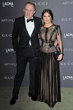 a man and woman standing next to each other on a green carpet