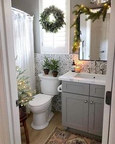 a bathroom decorated for christmas with wreaths on the window sill, toilet and sink