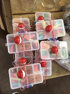 plastic containers filled with candy and candies on top of a wooden table next to wine glasses