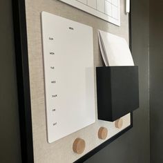 a white board mounted to the side of a wall next to a black and white clock