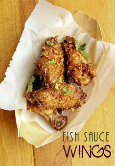 fish sauce wings in a basket on a wooden table with the words, fish sauce wings