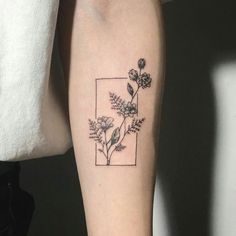 a black and white flower tattoo on the left arm with a square in the middle