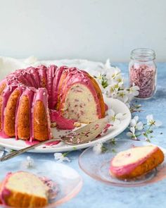 a bundt cake with pink icing on a plate next to two slices of it