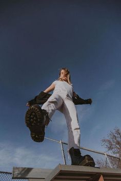 a man in white pants and black boots is doing a trick on a skateboard