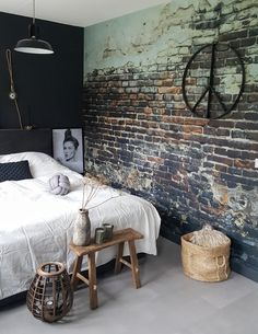 a bedroom with brick wall and white bedding, wooden stools and side table