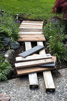 several pieces of wood are stacked on top of each other in the middle of a garden