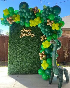 a green and yellow balloon arch with a giraffe on it's side