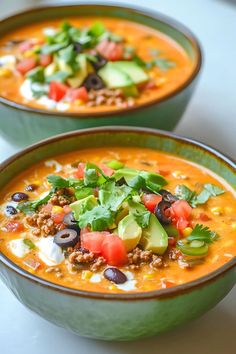 two green bowls filled with soup and vegetables