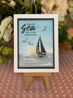 a card with a sailboat on it sitting on top of a wooden easel