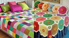 a bed covered in colorful crocheted bedspread with pillows and throw blankets