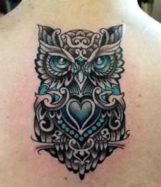 an owl tattoo on the back of a man's upper body, with blue eyes