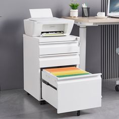 an office desk with a printer on top of it and a file cabinet under the desk