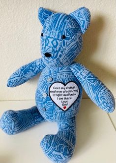 a blue teddy bear sitting on top of a white table next to a red heart