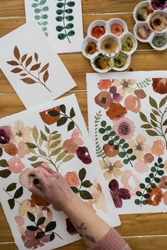 someone is painting flowers on paper with watercolors