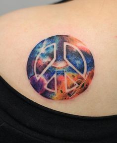 a colorful peace sign tattoo on the back of a woman's shoulder, with space in the background