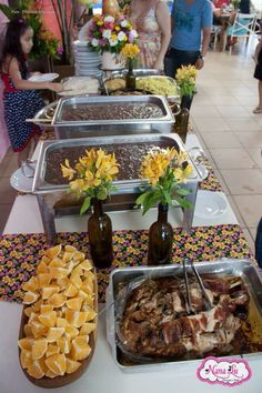 several trays of food sitting on top of a table with people standing in the background