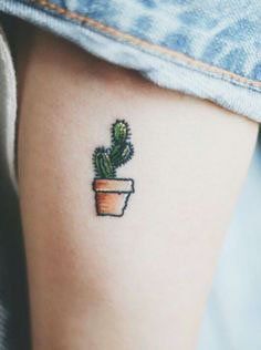 a small cactus in a pot tattoo on the arm