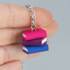 The cutest pride necklaces EVER! 🏳️‍🌈 Completely handmade from by our talented artist, this vibrant stack of books in the bisexual pride flag colors is the perfect way to show off who you are or who you support! These teeny tiny books are handmade to perfection, and you'll get tons of compliments (even if people don't recognize the flag colors!) More Pride Flag Jewelry 🏳️‍🌈 About this necklace: Flag Colors: Bisexual Size: approx 2 cm / 0.78 in height Materials: polymer clay Chain is 50 cm/ 1 Polymer Clay Chain, Clay Chain, Tiny Books, Pride Necklace, Bisexual Pride Flag, Pride Flag Colors, Stacked Necklaces, Book Stack, Flag Colors