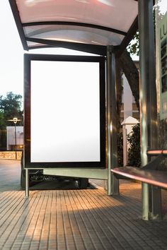 an empty bus stop with a large white screen on the side of it's door