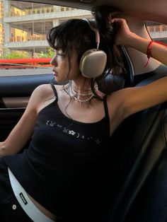 a woman sitting in the back seat of a car with headphones hanging from her ears