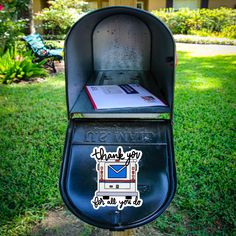 a mailbox with a sticker on it sitting in the grass