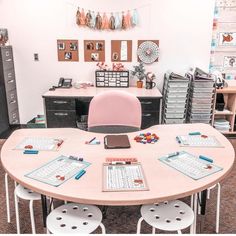 a pink table with four chairs and two laptops on it in an office setting