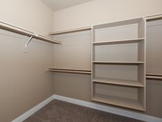 an empty walk - in closet with shelves and no doors