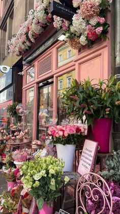 pink and white flowers on display in front of a flower shop