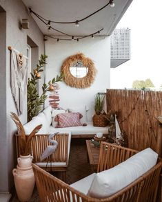 an outdoor living room with wicker furniture and plants on the wall, along with a round mirror