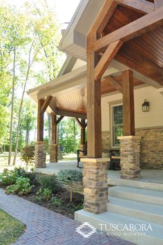 an outdoor covered porch with stone pillars and columns on each side, surrounded by brick pavers